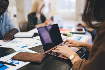 Crop woman working on laptop with blank screen in office