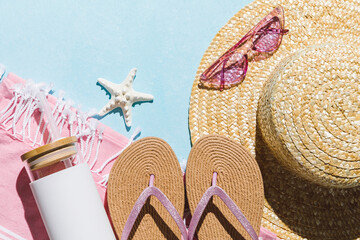 Summer flat lay with straw hat, sunglasses and beach accessories on blue background with trendy...