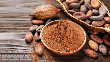 Cocoa powder and cocoa beans on wooden background