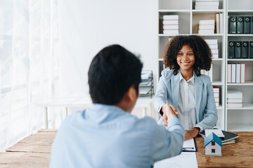 Fototapeta premium The bank's Female African american Mortgage Officers shake hands with customers to congratulate them after signing a housing investment loan agreement