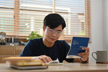 Young Asian man doing billing After looking at the water bill, electricity bill and passbook, The...