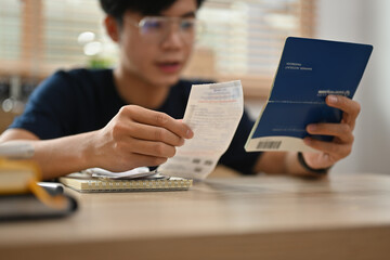 Close up and Cropped image of Young Asian man doing billing After looking at the water bill,...