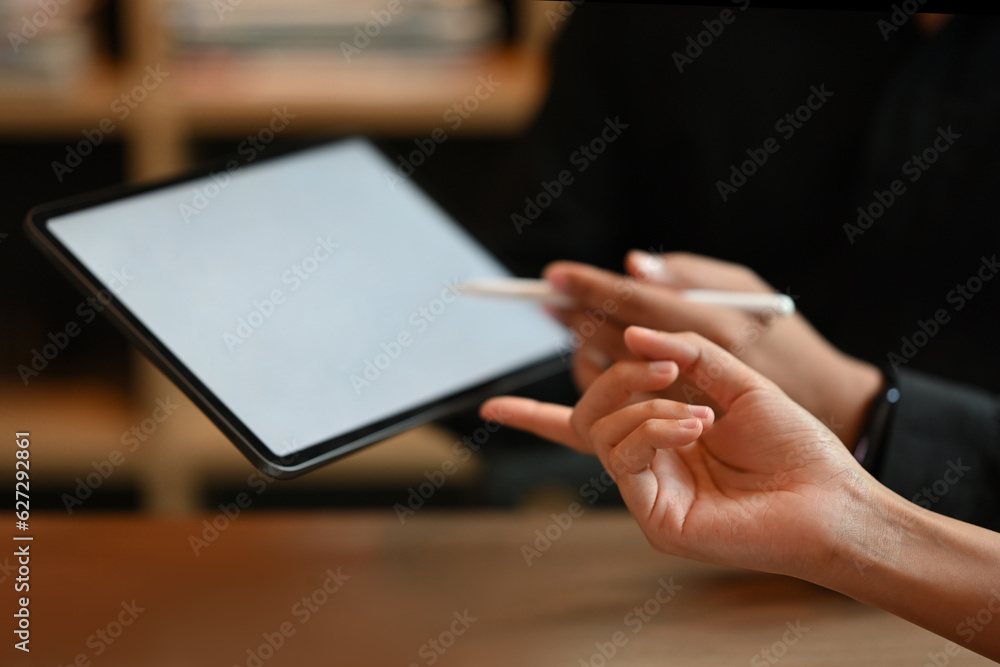 Poster close up and cropped image with hands pointing at screen of tablet.