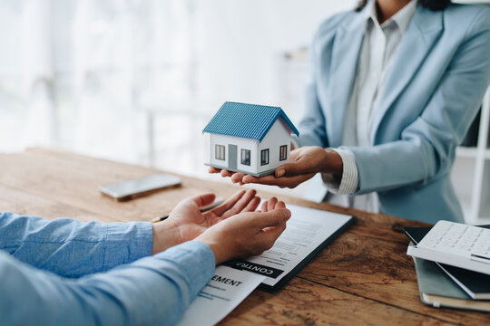 Female African american Real estate company to buy houses and land are delivering keys and houses to customers after agreeing to make a home purchase agreement and make a loan agreement.