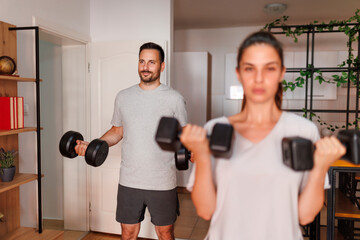 Couple lifting weights while working out together at home