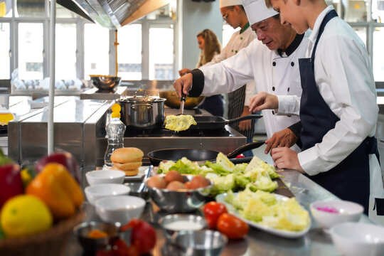 Select focus. Chef teacher teaches cooking to the group children in class kitchen room.  Chef preparing student for learning marking and cooking food at workshop.  Education Concept