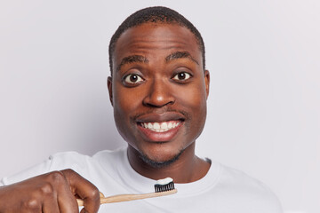 Young black short haired man diligently brushes his teeth taking care of oral hygiene maintaining...