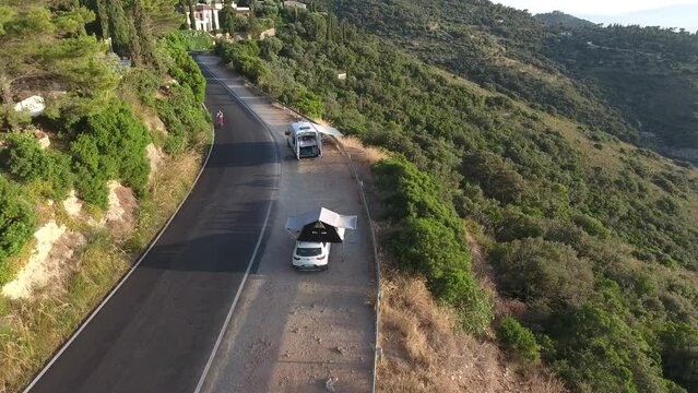 People with vans and rooftop tend park in a road close to the sea in Argentario Island, Tuscany, Italy