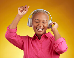Music headphones, smile and black woman dancing in studio isolated on a yellow background. African...