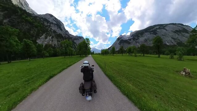 Motor biker is riding through the Ahornboden in the Karwendel Mountains in the Austrian Alps with a view of the mountains in panoramic perspective and tiny planet - Video and Audio