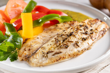 Grilled tilapia fillet with spices and colored peppers.