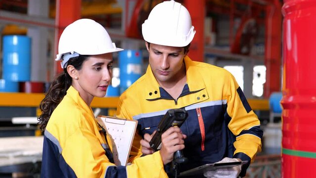 VDO 4K slow motion of male and female auditor wearing safety uniform workwear with handheld barcode scanner or rfid handheld reader and tablet computer count goods in warehouse of factory Manufacture.