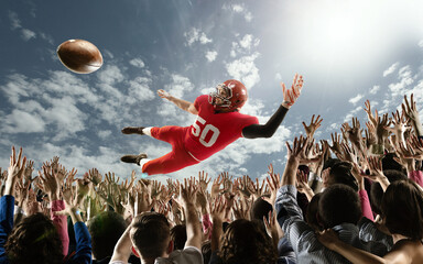 Professional american football player flies over hands of fans and catching a touchdown pass.