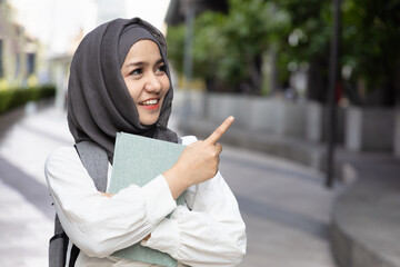 Young Muslim Woman Student pointing, showing something. Back to School, Education awareness,...