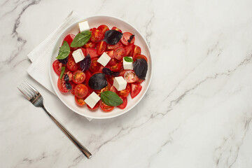 Salad with tomatoes, feta and basil on a gray background