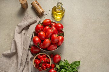 Culinary background. Tomatoes in a plate, spices and oil on a gray background
