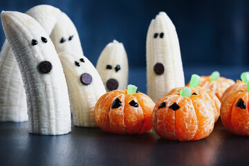 Halloween cute pumpkin orange fruit and scary banana ghosts monsters with chocolate faces. Healthy...