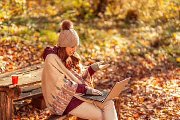 Woman having video call while spending autumn day outdoors