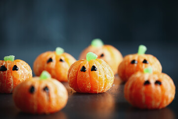 Halloween cute pumpkin orange fruit with chocolate eyes. Healthy dessert snack with funny faces for...