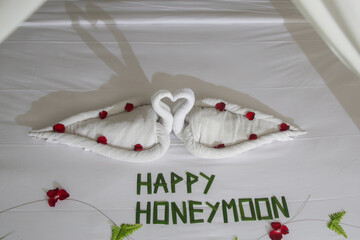 Luxury hotel bedroom interior with honeymoon decoration, Towel swans and rose flowers on the bed	