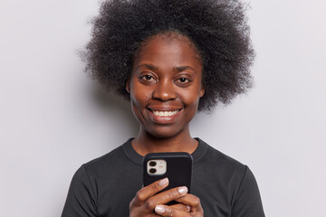 Stylish African woman holds smartphone captivated by the screens content has focused expression she effortlessly navigates through digital world effortlessly blending modern technology with presence