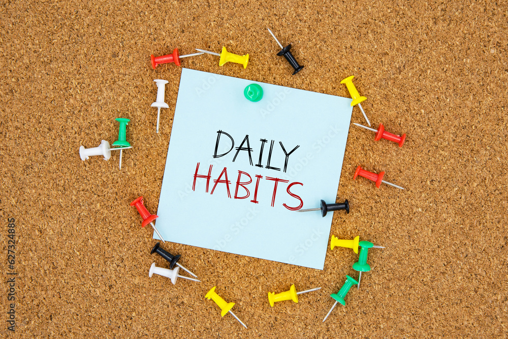 Poster daily habits text on light blue post-it paper pinned on bulletin cork board surrounding by multi col