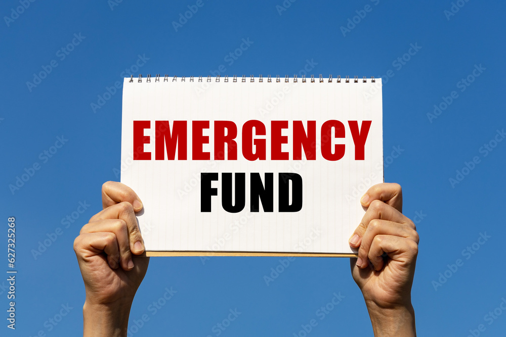 Poster emergency fund text on notebook paper held by 2 hands with isolated blue sky background. this messag