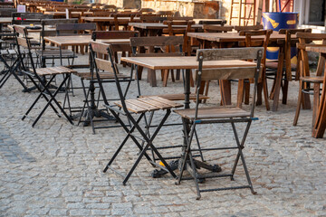 wooden folding iron chairs and tables placed on the street in front of a cafe