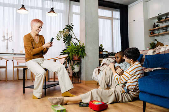 Mature lesbian couple taking photo on cellphone with their adopted child