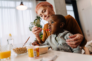 Mature white woman feeding her adopted child at home