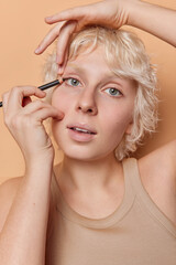 Vertical shot of beautiful woman applies eyeliner with precision accentuating her eyes and enhancing natural beauty applies makeup dressed in casual t shirt unveiling unique style and elegance.