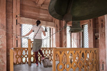 Bell ringer a woman rings the bells. Christian Voznesenskiy Cathedral in the center of Almaty city. Orthodox christian church. The bell tower of the Cathedral. Panfilov park.