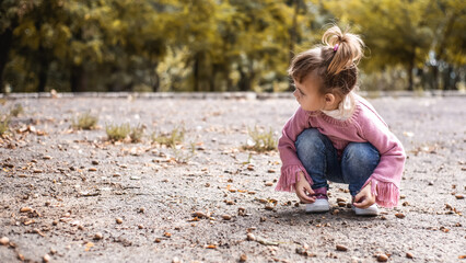 Positive little girl playing in the autumn park. Happy emotional child catches maple leaves. active holiday in autumn. leaf fall