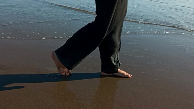Video of barefoot footsteps on a sandy beach. Walk along the ocean shore