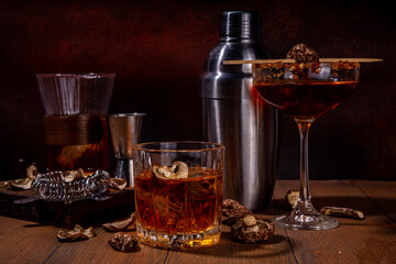 

Trendy hard alcohol mushroom cocktail, booze-free mushroom infused drinks in various cocktail glasses, with bar utensils on dark wooden background copy space