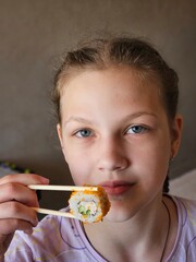 Cute smiling girl with with sushi. Student child girl eating sushi and rolls - commercial concept. young girl eating rolls sushi.
