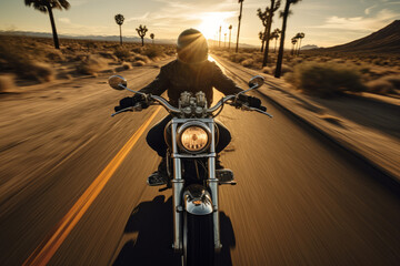 Front view of a biker riding a vintage motorcycle galloping on US Route and natural American landscape