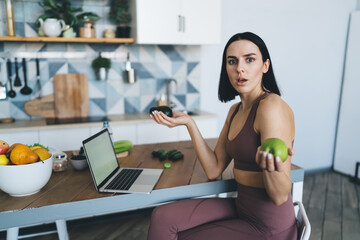 Puzzled woman with laptop and fruits