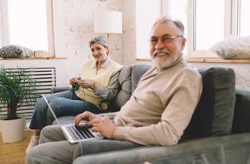 Happy elderly married couple sitting on couch