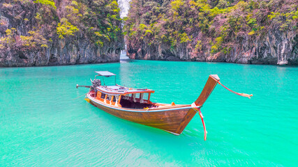 Naklejka na ściany i meble Tourist long tail boat Landed on a peaceful beach, clear water, surrounded by hills of Koh Phi Phi, Thailand