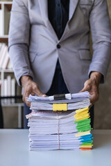 Young businessman working in office sorting piles of graphic papers on table vertical image