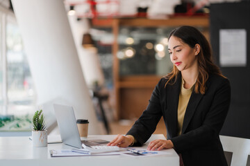 Asian businesswoman working online with financial documents and laptop on table in office Finance and Business Accounting business training concept