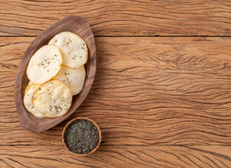 Fototapeta na wymiar Smoked provolone cheese chips in a bowl with oregano over wooden table with copy space