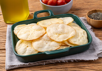 Smoked provolone cheese chips in a bowl with cherry tomatoes and oregano over wooden table
