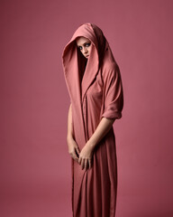 Portait of beautiful woman wearing gown of draped silk fabric, standing pose. Isolated on pink...