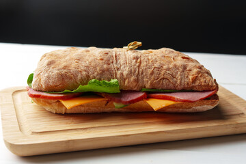 Chiabatta sandwich with ham and cheese on wooden board