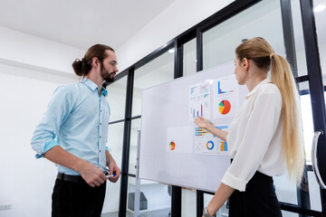 Female manager pointing finger graph and looking at presentations on whiteboard in meeting room. Business people, present their investment in company. Business project planning target.
