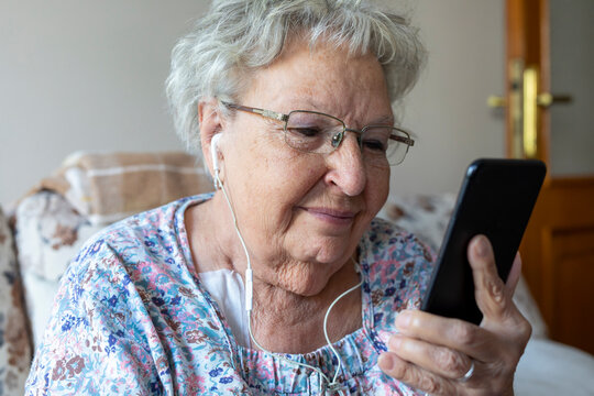 Happy elderly woman enjoying using mobile apps,  smiling senior woman holding smartphone, looking at mobile phone screen, browsing social media at home