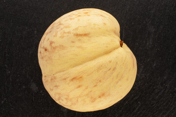 One juicy ripe peach on black ceramic, macro, top view.