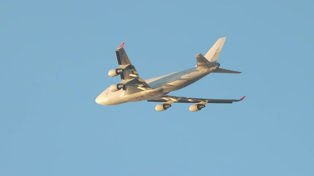 Generic Unmarked 747 Type Jumbo Cargo Jet Airliner Flying International Logistics into Golden Hour Sunlight in a Blue Sky